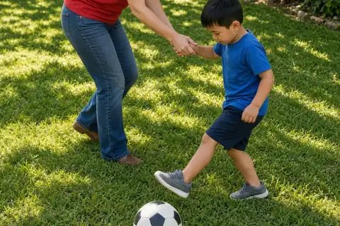 A mother and her young son in a sunny backyard kicking a soccer ball together